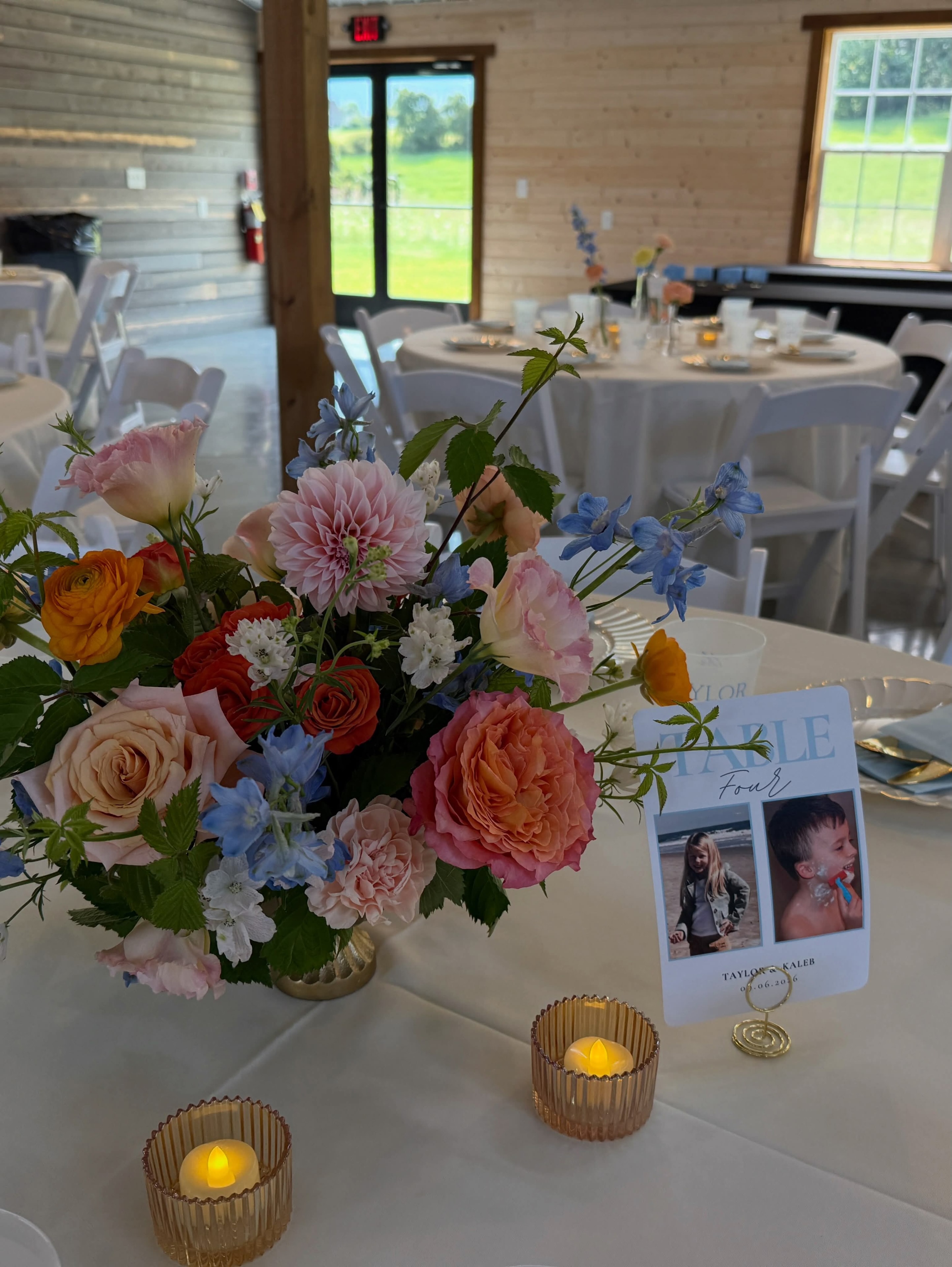 Colorful floral centerpiece with dahlias, roses, and blue delphinium