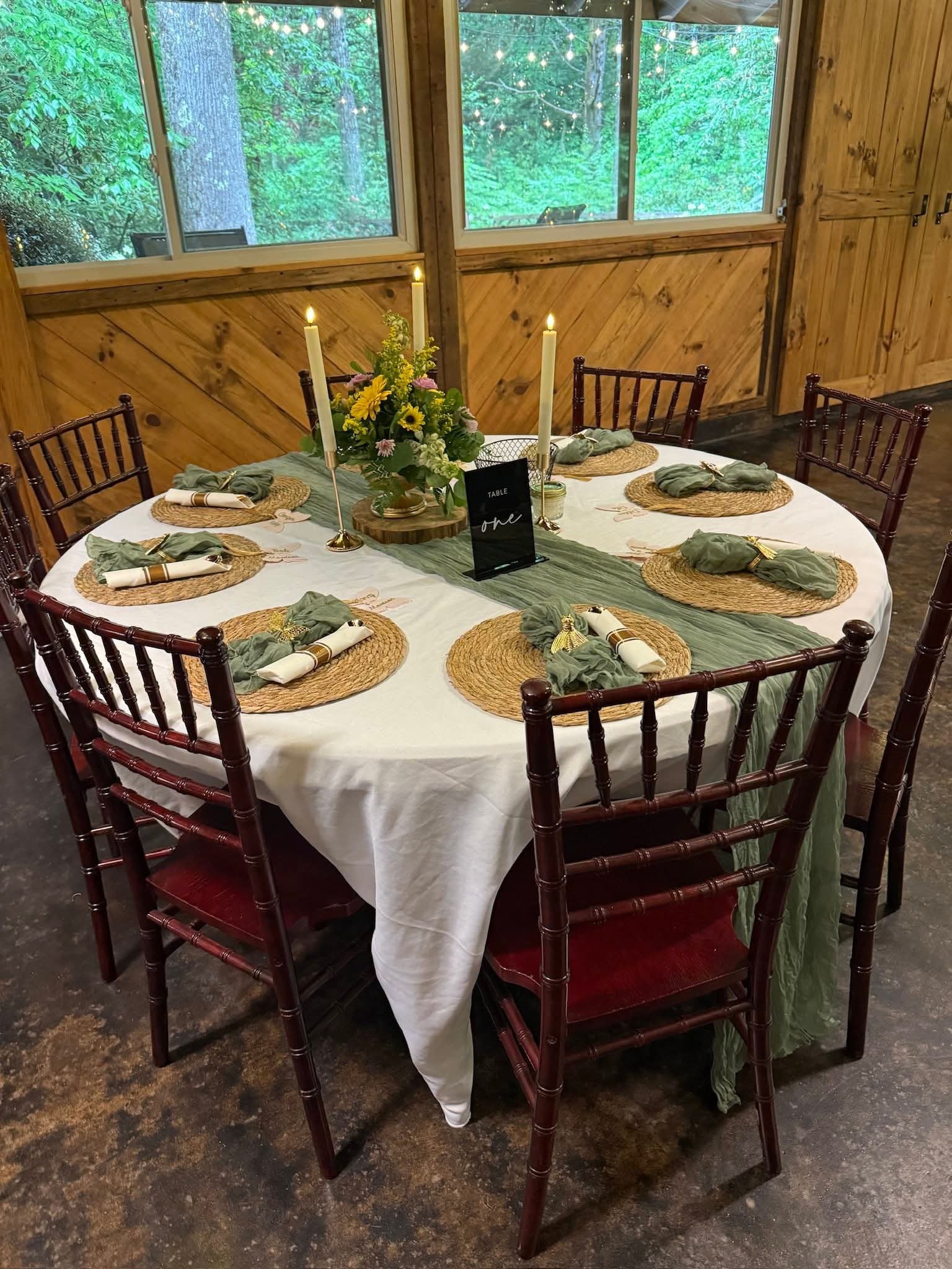 Round table with sage green runner and sunflower centerpiece in a barn